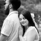 Pareja de preboda en blanco y negro, mujer recostada sobre la espalda de hombre mirando el horizonte con esperanza.