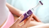 a woman is holding a purple electric toothbrush