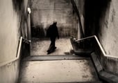 Lone figure walking down a concrete stairwell in a moody urban fine art photograph