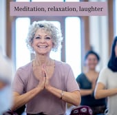 Lady in yoga pose smiling in a class
