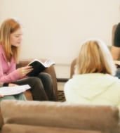 Group of diverse people in living room holding Bibles, sharing enlightenment concepts