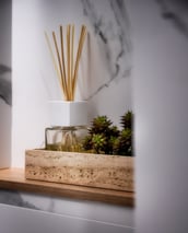 Un jarrón con una planta y un ambientador en un estante.