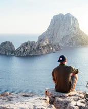 a man sitting on a rock formation in the ocean