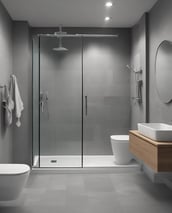 A modern bathroom showroom featuring a toilet, a glass shower enclosure, and dark tile flooring. The walls incorporate built-in cabinetry with minimalist designs. A wicker basket and some packaged products are visible under a counter.