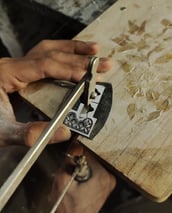 a person is using a pair of scissors to cut a piece of wood