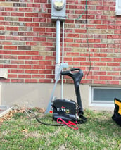 Utility location equipment leaning against a power utility meter