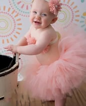 a happy, smiling baby girl in a pink tutu with a matching headband