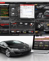 A single-story building with the words 'AUTO REPAIRING' displayed prominently above a series of windows. The structure appears weathered, with some paint peeling off, indicating age and exposure to the elements. The scene is set on a clear day with a bright blue sky, and the ground in front of the building is covered in gravel or dirt. A small, corrugated metal structure is attached to the side of the building.