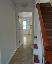 a hallway with a staircase and a tiled floor