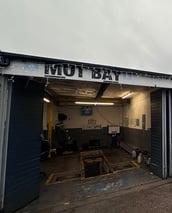 a garage with a garage door open and a sign that says MOT Bay