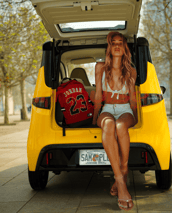 young woman sits in the rear hatch opening of Impulse Electromotive Nano-3 Micro EV car