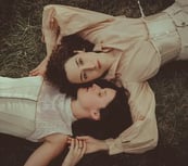 "Pareja lesbiana vista desde arriba, abrazándose en el suelo, celebrando el amor en una boda gay."