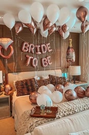 Luxury hotel room decorated with “Bride to Be” banners, balloons, and fresh flowers.