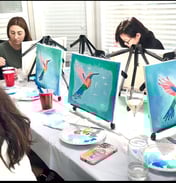 paint party women sitting at a table with art work