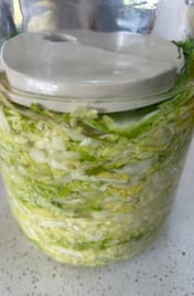 sauerkraut in a jar with a ceramic weight