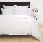 a bed with white sheets and pillows on a bed