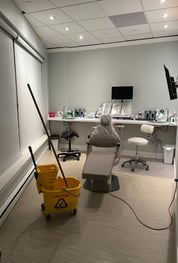 A dental office room with a chair in it and a mop in a bucket.