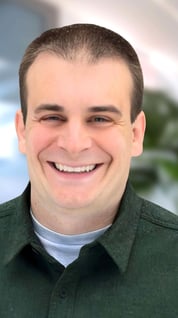 a man in a green shirt smiling at the camera