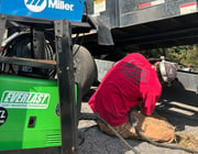 a ma repairing a trailer with a everlast welder next to him