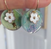 a person holding a pair of earrings with flowers