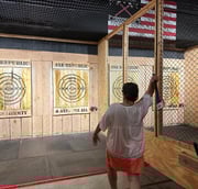 a woman is holding an axe and aiming a target