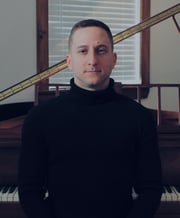 Photograph of Canadian composer Travis Reichstein in front of a piano