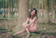 a woman sitting on a tree stump in a park