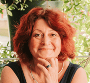 Flo Salort assise, main sous le menton, exprimant bienveillance, joie et leadership féminin