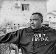 a man wearing a black jacket, siting down and look sideways