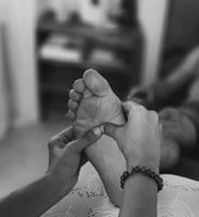 main prodiguant un soin réflexologique sur des pieds