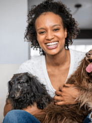 A beautiful young black woman holding her two elderly dogs