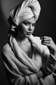 Schwarz-Weiß-Porträt einer jungen Frau in Bademantel und Handtuchturban, die verführerisch blickt.
