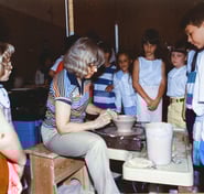 Naoma Powell throwing on the wheel in front of a class of elementary students.