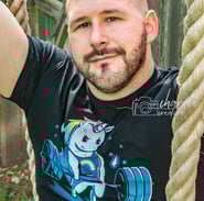 young bald, bearded man on rope swing with weight-lifting rainbow unicorn on shirt