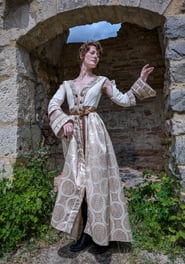 Femme en robe blanche et beige médiévale fantastique dans un fond de château en ruines