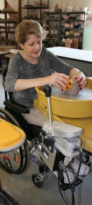 Woman in a wheelchair throwing on our wheelchair-accessible potter's wheel.