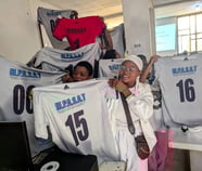 girls holding white jerseys with numbers on