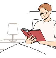 a man reading a book in bed with a lamp on the side