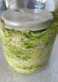 sauerkraut in a jar with a ceramic weight