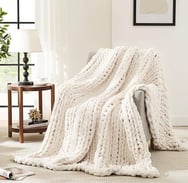 a white knitted blanket on a couch
