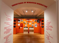 an orange exhibition display of portraits and text, bordered by a white wall with orange text