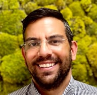 a man with a beard and glasses on a green background