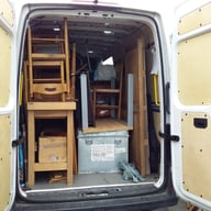 Fourgon de déménagement chargé de meubles en bois, boîtes en carton, objets emballés et caisses métalliques, prêt pour le tra