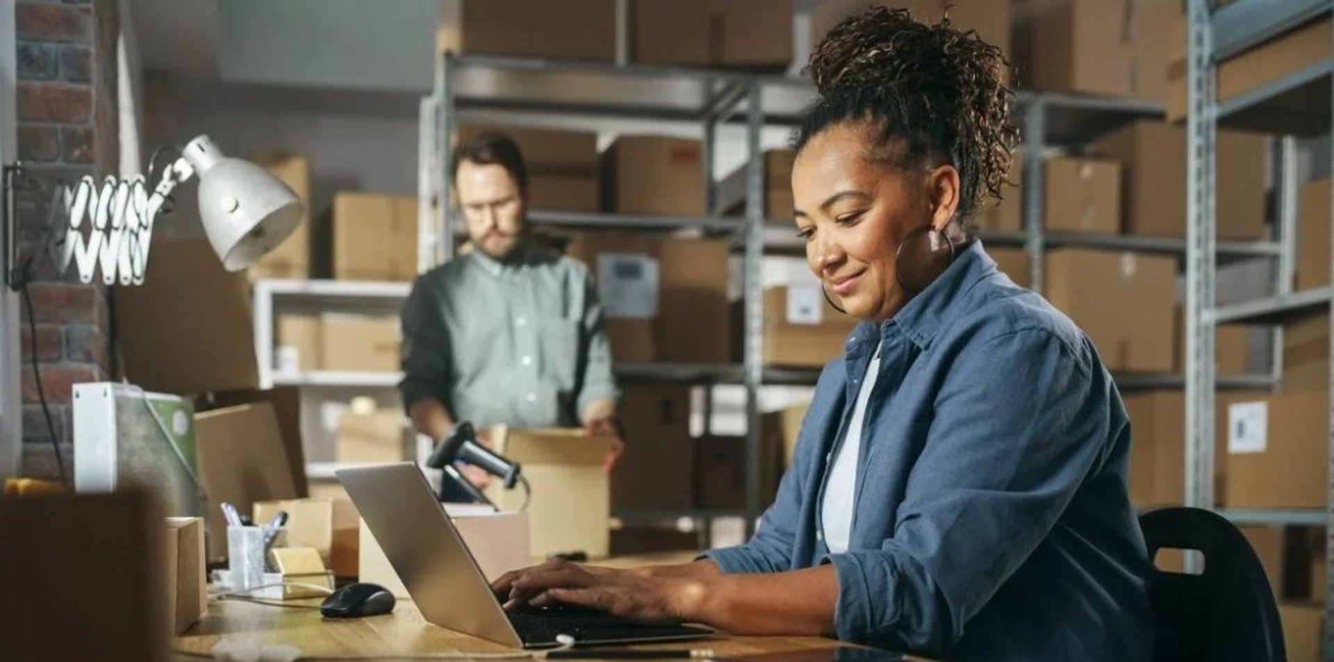 Mulher empreendedora trabalhando em notebook em armazém de e-commerce, representando o público-alvo de gestão contábil