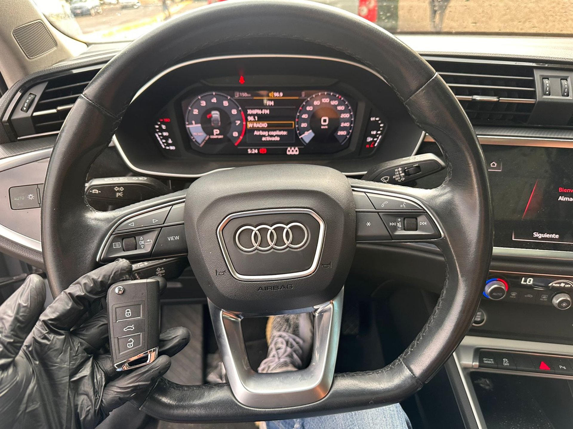 Hand holding car key in front of black porsche