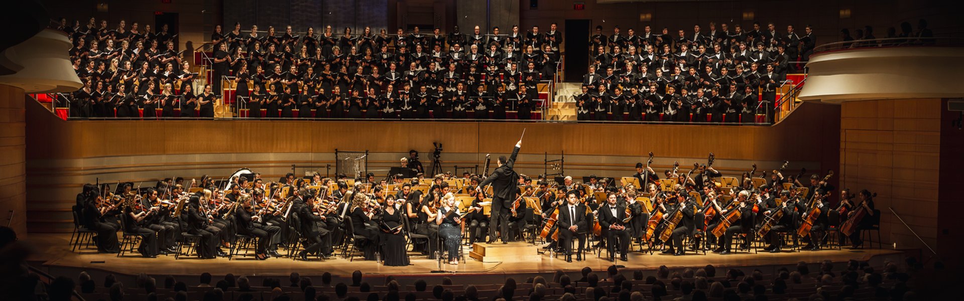 Conductor leading orchestra with baton over sheet music