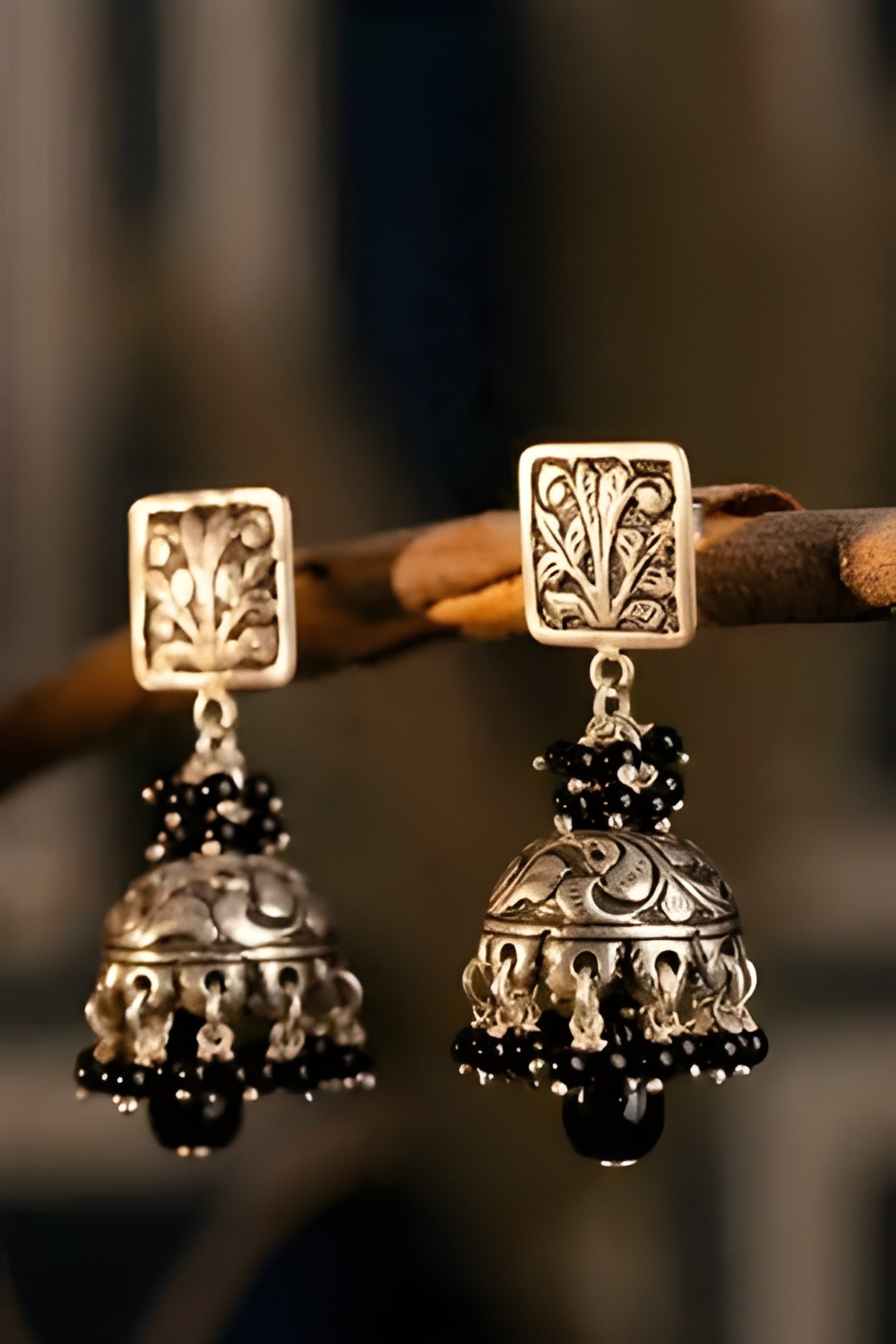 A pair of silver bells hanging from a tree branch