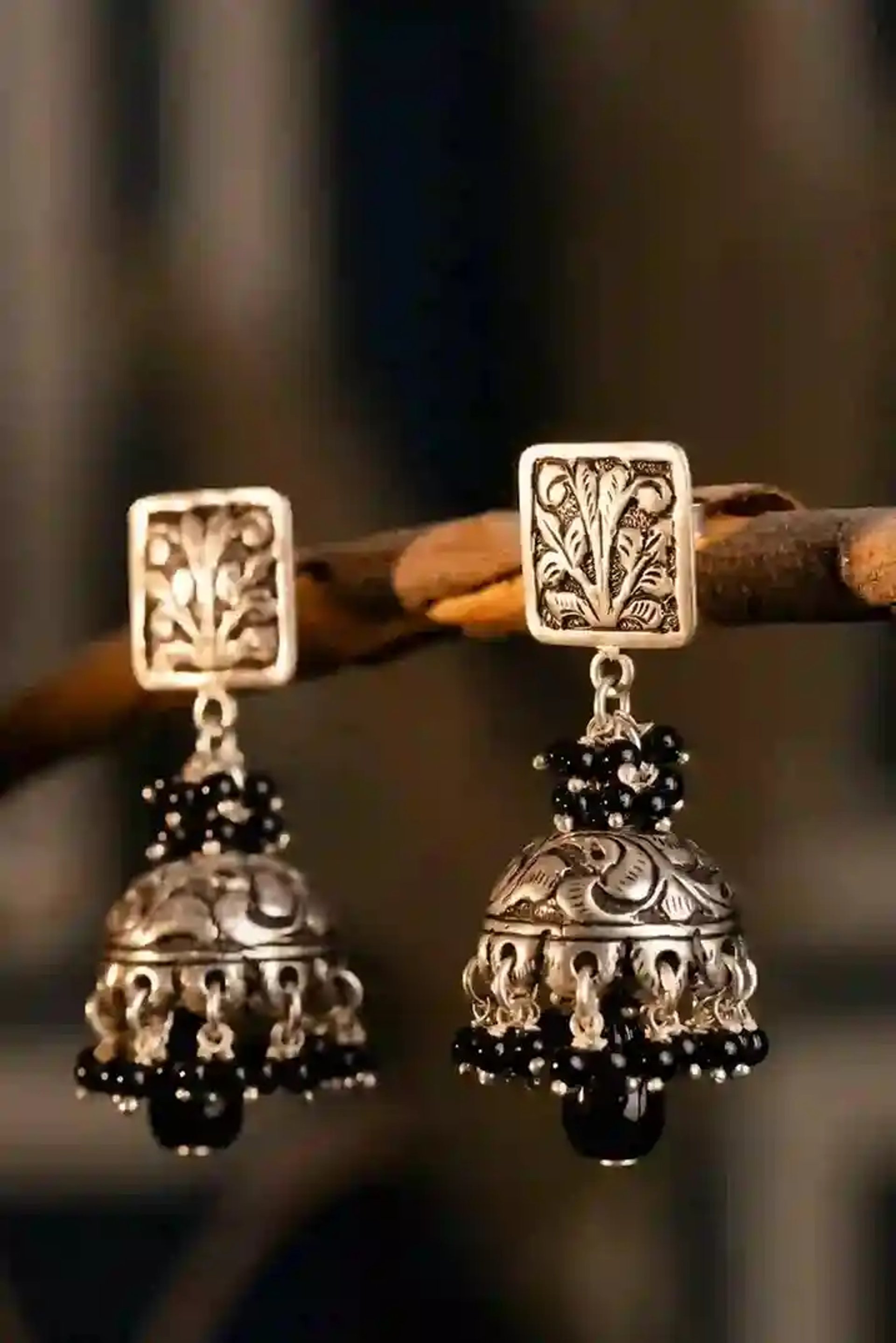 A pair of silver bells hanging from a tree branch