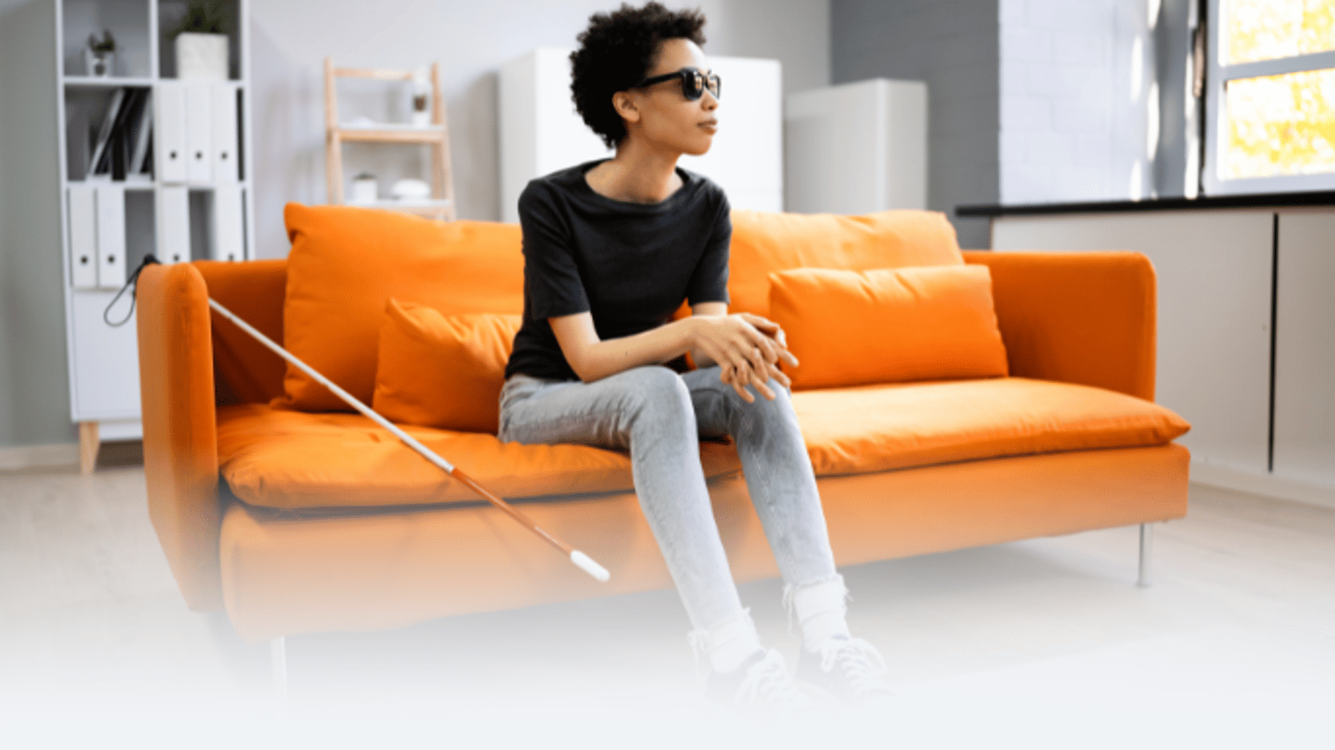 professional  woman with astigmatism blind  low vison woman with cane on orange couch wearing cocoon  glare shields