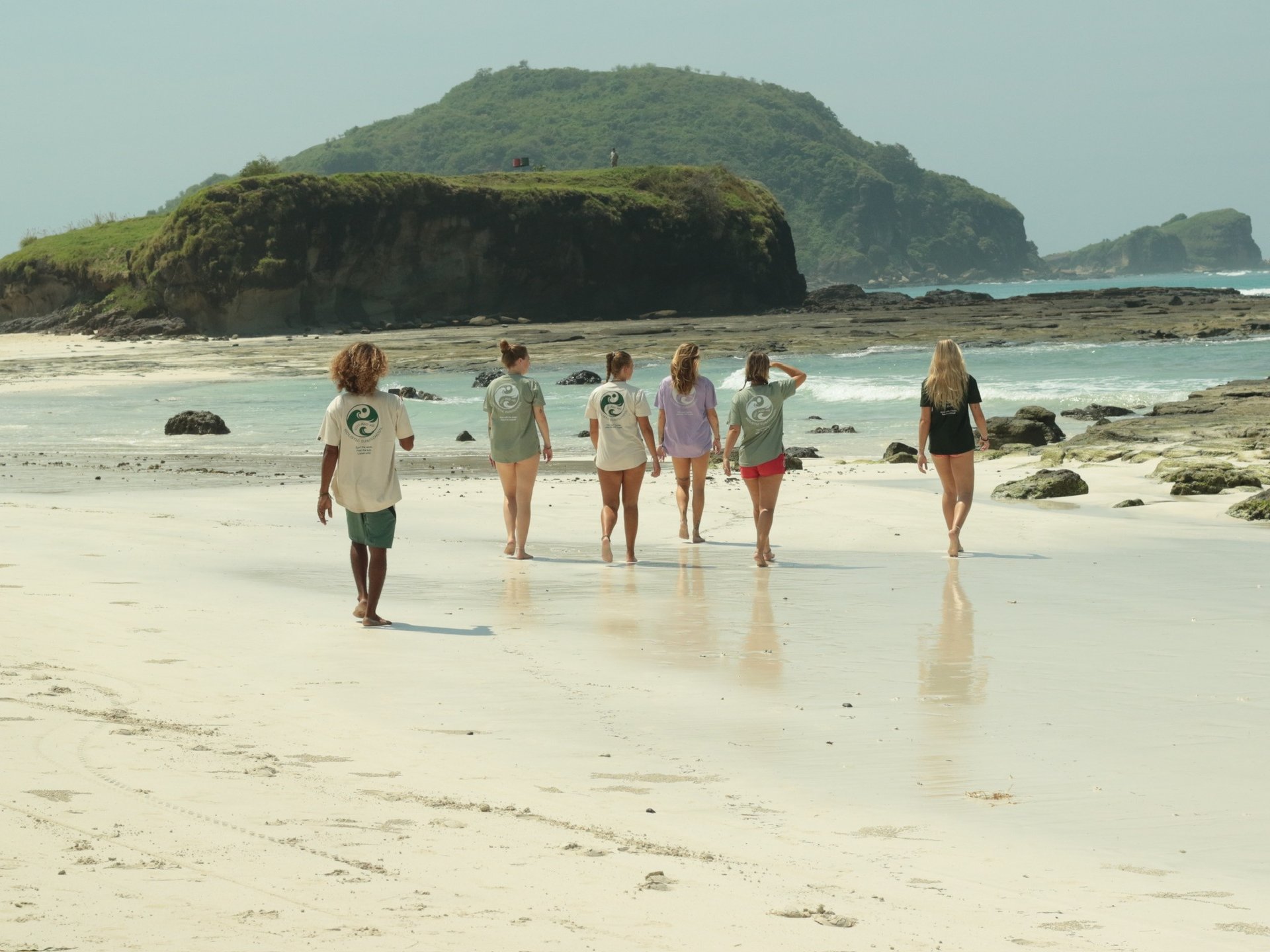 two women walking towards the ocean carrying surfboards during day